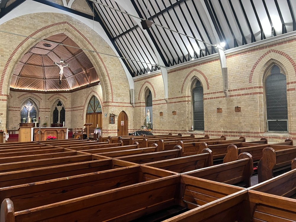 Interior of St. David & St. Helen, Caernarfon, with pews and crucifix