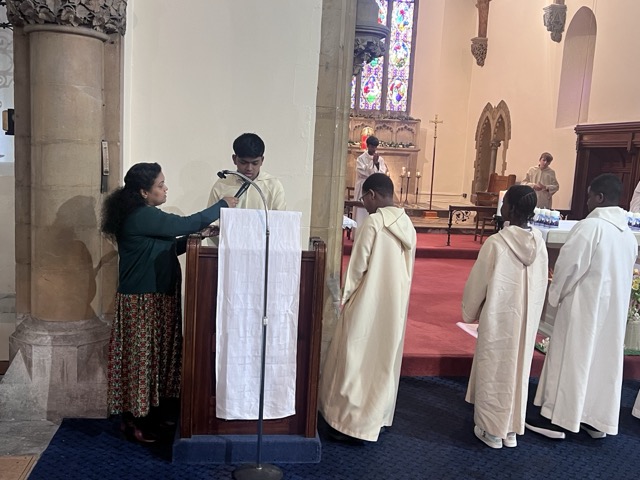 A reader at the lectern with altar servers nearby