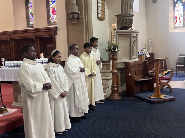 A row of altar servers standing beside the sanctuary