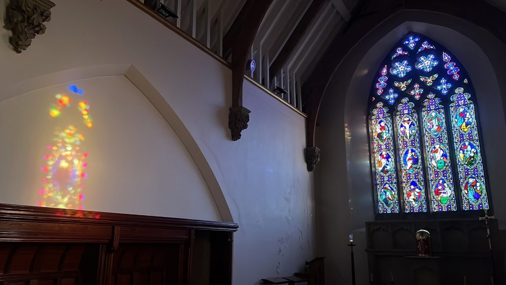 Rainbow light from the stained glass cast on the nave wall