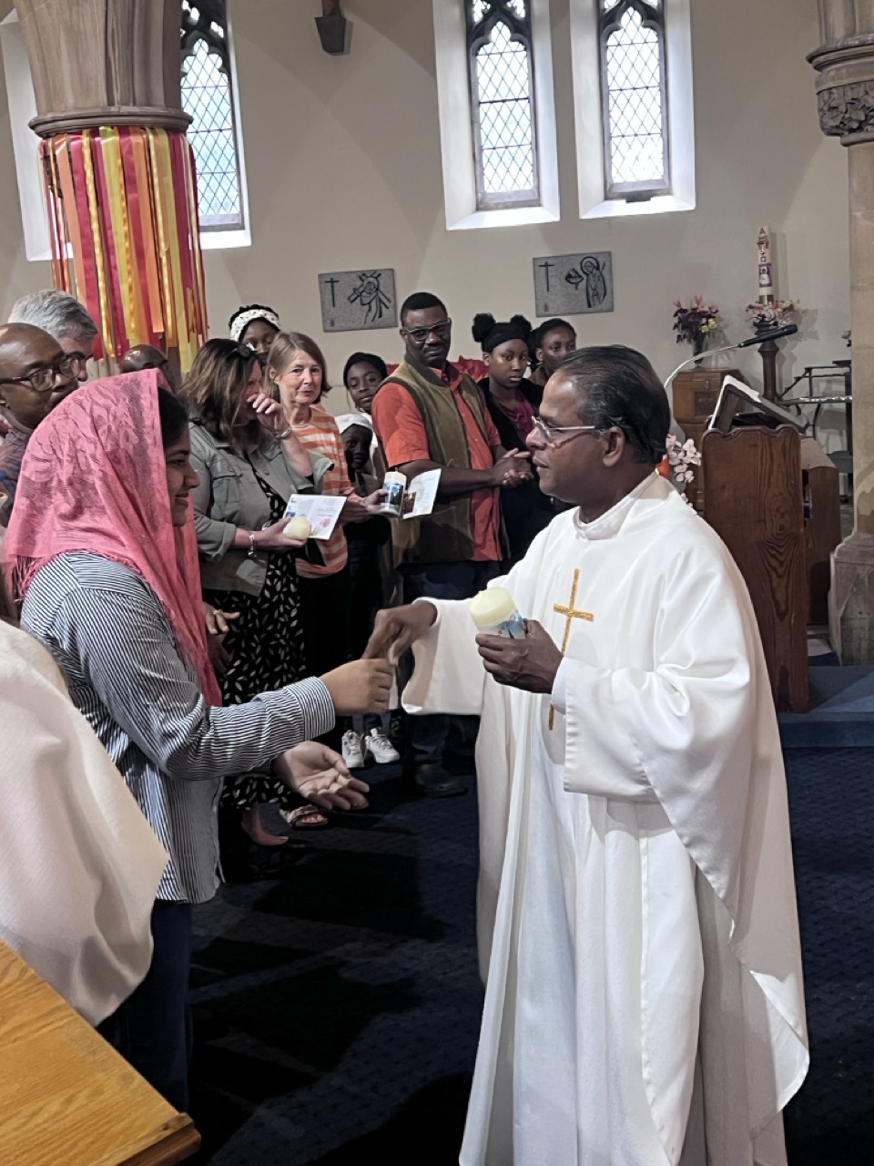 Fr. Savi handing a candle to a young person
